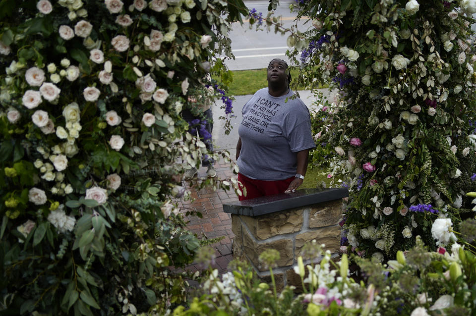 Raekeisha Watkins visits flowers left as a memorial for the Tulsa Race Massacre near the historic greenwood district during centennial commemorations of the massacre, Monday, May 31, 2021, in Tulsa, Okla. (AP Photo/John Locher)