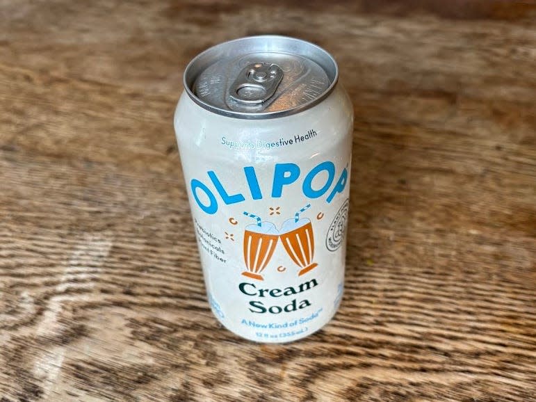 A can of cream-soda Olipop on a wooden table.