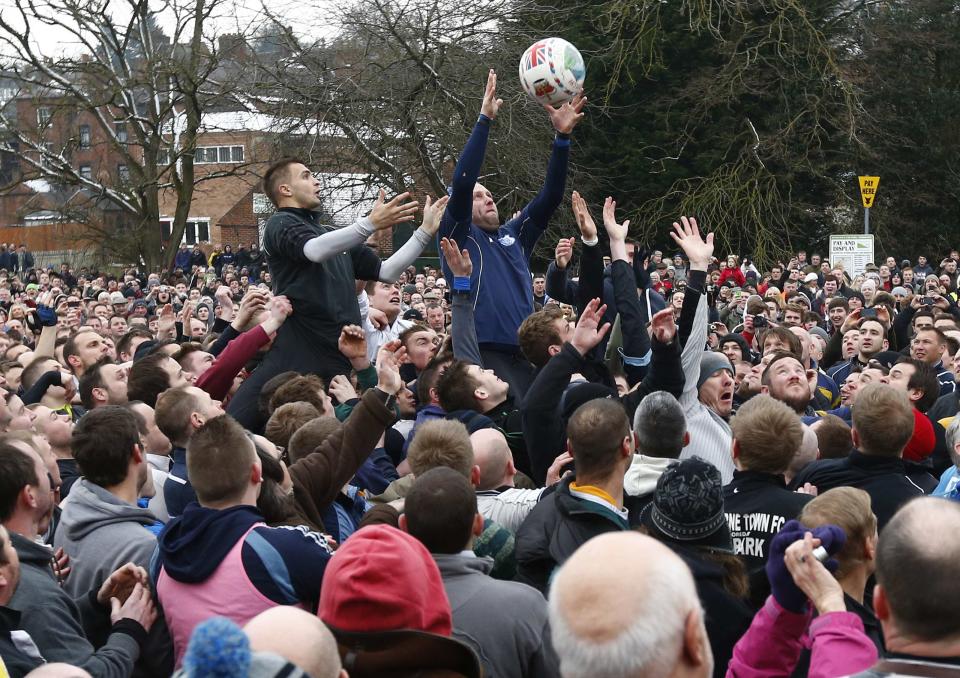 �The ball is thrown into the hug to start the annual Shrovetide football match (Reuters)