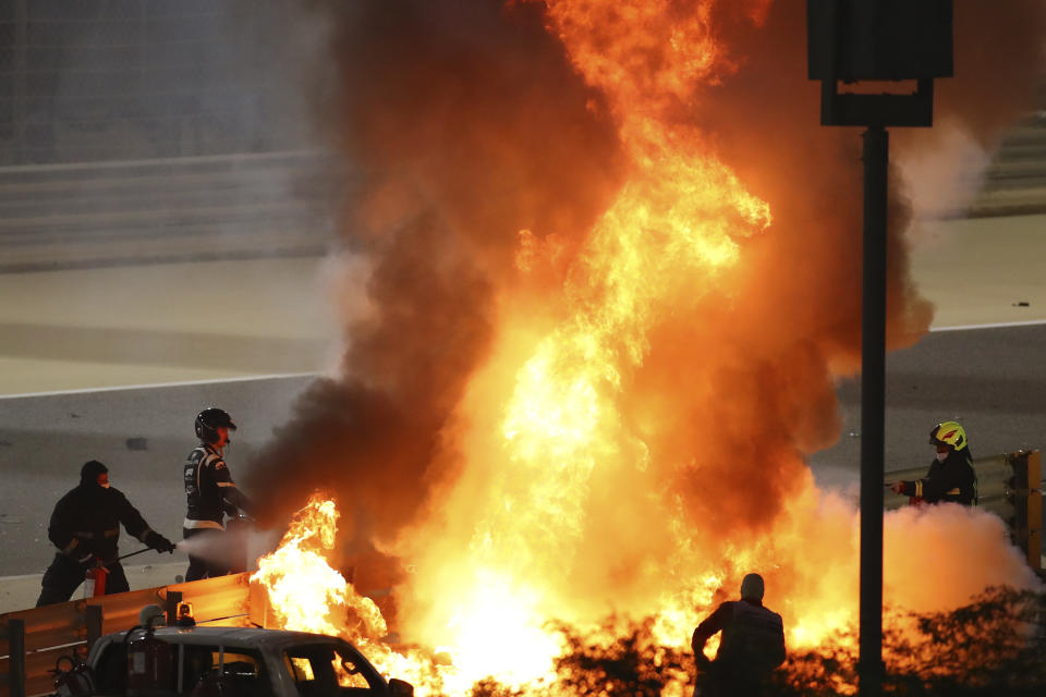 FILE - Staff extinguish flames from Haas driver Romain Grosjean's car after a crash during the Formula One race in Bahrain International Circuit in Sakhir, Bahrain, in this Sunday, Nov. 29, 2020, file photo. Mercedes announced Wednesday, May 5, 2021, that Grosjean will drive Lewis Hamilton’s 2019 championship-winning car at the French Grand Prix on June 27 before a full test day at Circuit Paul Ricard two days later. (Brynn Lennon/Pool via AP, File)