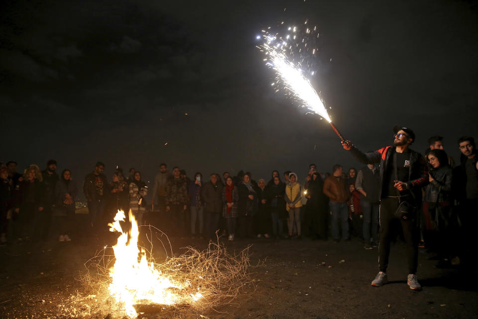 A man holds up a firework during Chaharshanbe Souri, or Wednesday Feast, an ancient Festival of Fire, on the eve of the last Wednesday of the solar Persian year, in Tehran, Iran, Tuesday, March 19, 2019. Iran's many woes briefly went up in smoke on Tuesday as Iranians observed a nearly 4,000-year-old Persian tradition known as the Festival of Fire. (AP Photo/Ebrahim Noroozi)