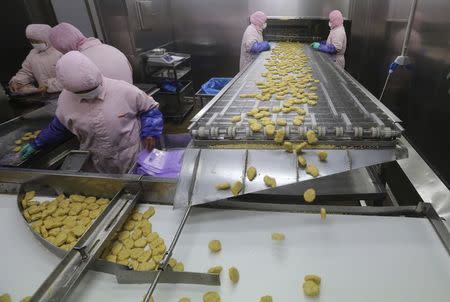 Employees work at a production line prior to a seizure conducted by officers from the Shanghai Food and Drug Administration, at the Husi Food factory in Shanghai, July 20, 2014. REUTERS/Stringer