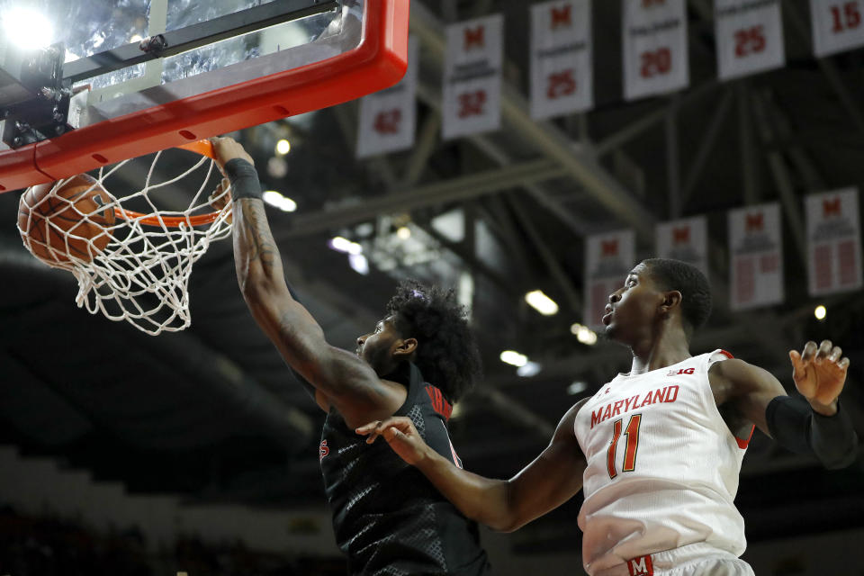 Rutgers center Myles Johnson, left, dunks next to Maryland guard Darryl Morsell during the first half of an NCAA college basketball game Tuesday, Feb. 4, 2020, in College Park, Md. (AP Photo/Julio Cortez)