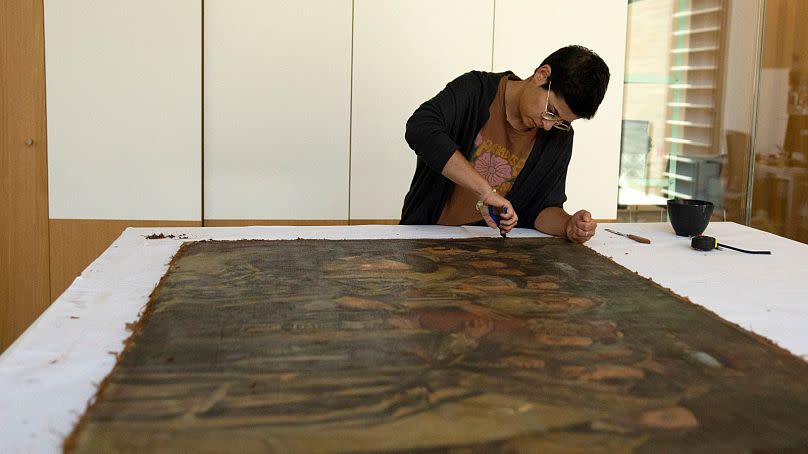 Sarah Reichert restores a painting in a conservation lab during the inauguration of The Moshal Shoah Legacy Campus and The David and Fela Shapell Family Collections Center