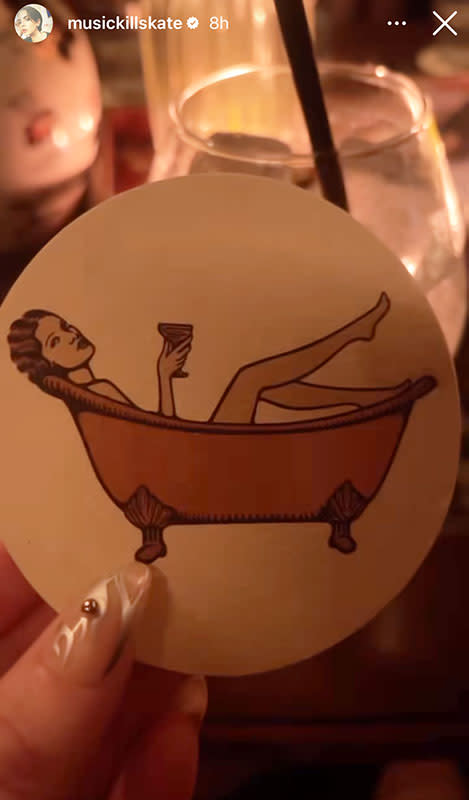 Katie Maloney holding a coaster with an illustration of a woman in a bathtub holding a wine glass with her marbled nails.