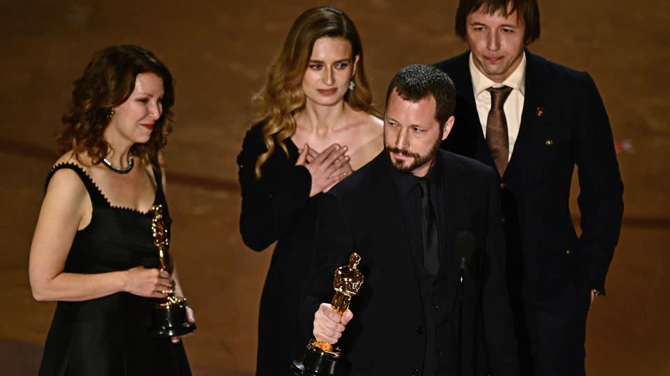 Ukrainian filmmaker Mstyslav Chernov (C), flanked by (from L) Raney Aronson-Rath, Vasilisa Stepanenko and Evgeniy Maloletka, accepting the award for best documentary feature for  "20 Days in Mariupol." - Patrick T. Fallon/AFP/Getty Images