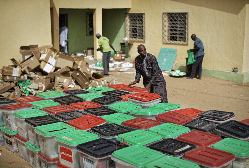 An electoral worker carries and stacks ballot boxes at an electoral commission office in Kano, in northern Nigeria Sunday, Feb. 24, 2019. Vote counting continued Sunday as Nigerians awaited the outcome of a presidential poll seen as a tight race between the president and a former vice president. (AP Photo/Ben Curtis)