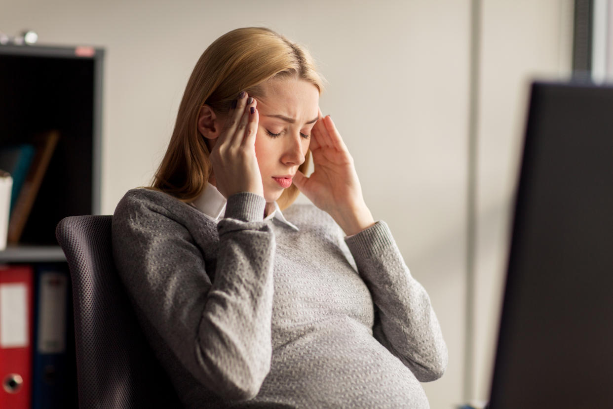 Pregnant businesswoman suffering from headache or stress at office
