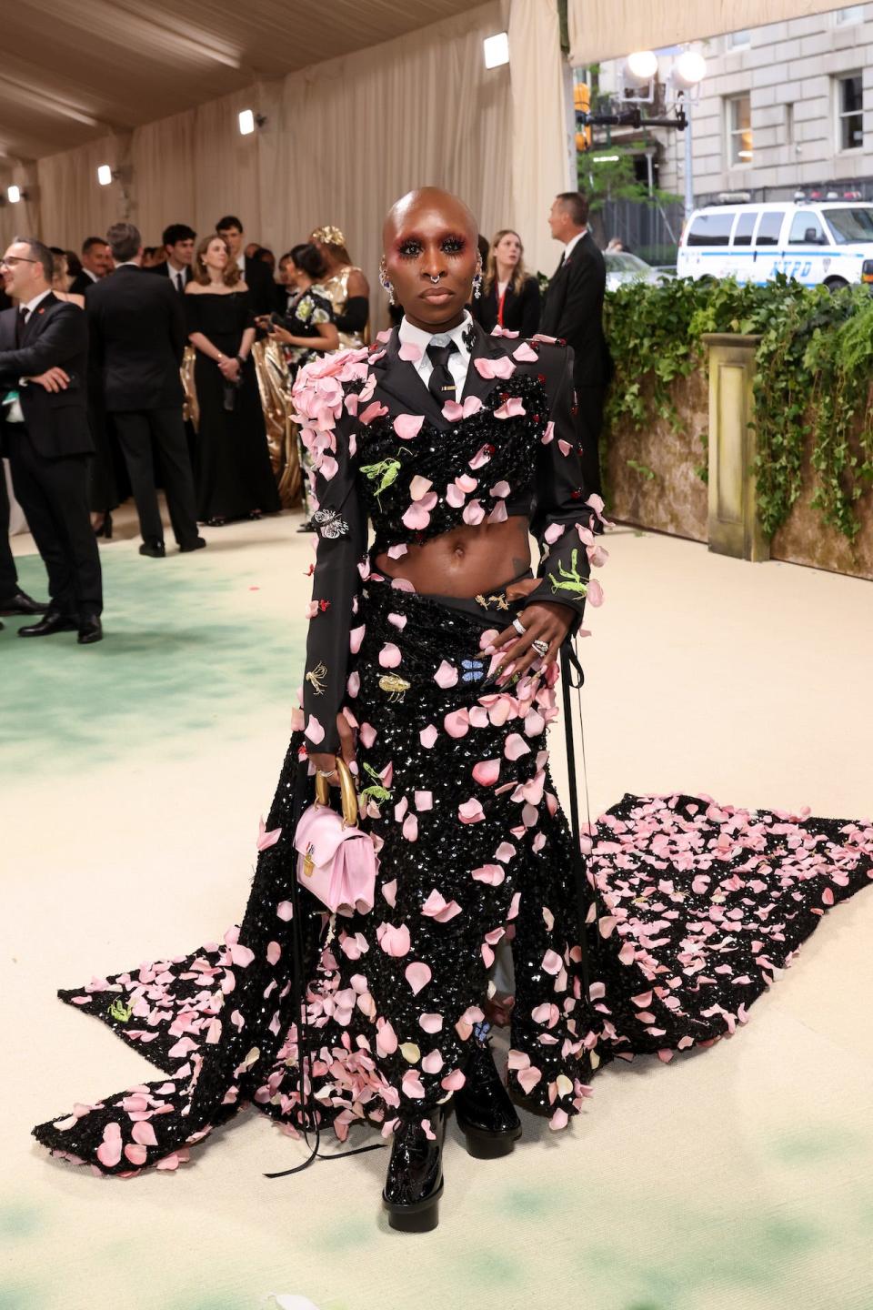 Cynthia Erivo wearing a flower petal covered black cropped blazer and skirt with a train.