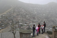 In this Sept. 27, 2018 photo, a family watches the official caravan of Peru's President Martin Vizcarra drive away, after his visit to the Flor de Amancaes shantytown in Lima, Peru. Few thought that the bespectacled substitute president, who had no political party and faced an opposition majority in Congress, would last very long. (AP Photo/Martin Mejia)