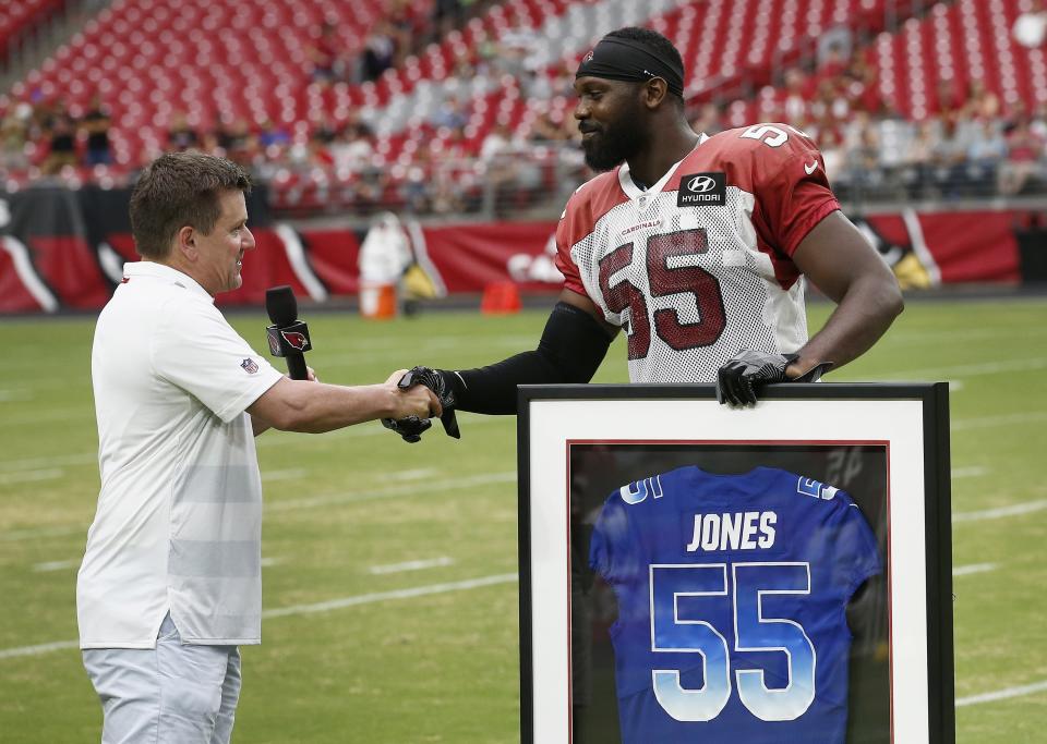 Arizona Cardinals defensive end Chandler Jones (55) shakes hands with team president Michael Bidwill, left, as Jones receives a framed Pro Bowl jersey from the team prior to an NFL football practice Saturday, Aug. 4, 2018, in Glendale, Ariz. (AP Photo/Ross D. Franklin)