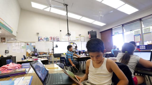 Angel Urquia wears a tank top as he studies under whirling ceiling fans that provide little relief in a hot classroom.