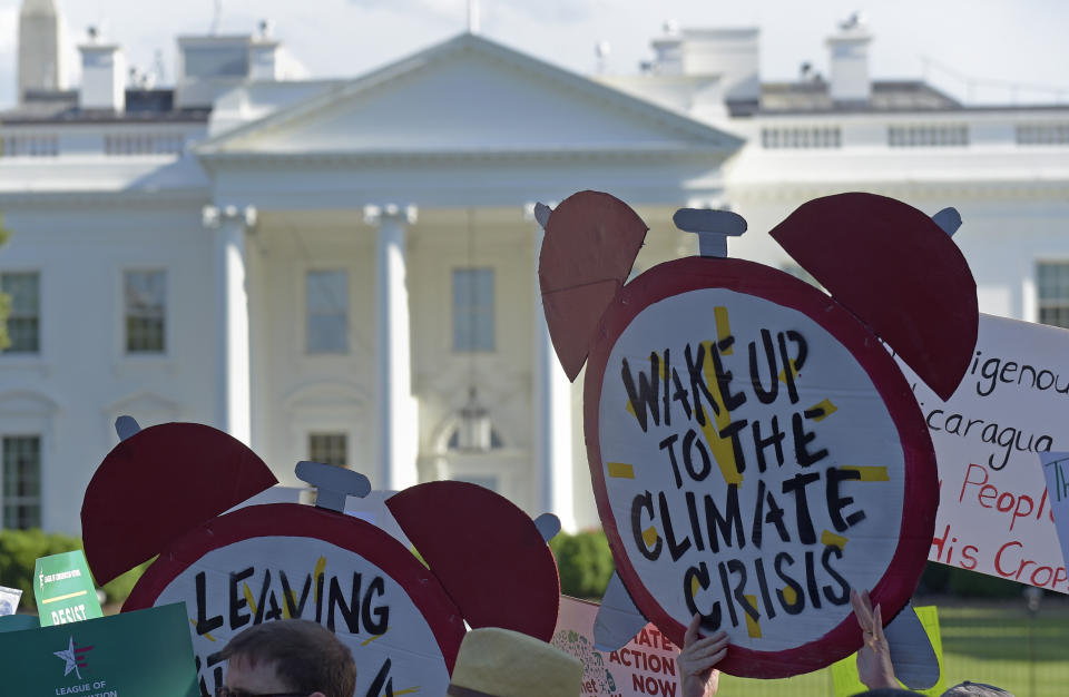 FILE - In this June 1, 2017 file photo, protesters gather outside the White House in Washington to protest President Donald Trump's decision to withdraw the Unites States from the Paris climate change accord. Environmental activists are ramping up a pressure campaign aimed at stoking Democratic support for an ambitious environmental plan known as the Green New Deal ahead of the 2020 presidential race. (AP Photo/Susan Walsh)