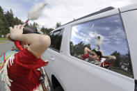 In this photo taken Saturday, April 4, 2020, Wicahpi Cuny, 14, a Dakota and Lakota tribal member, uses the reflection in her family's car window to prepare her headdress before a live streamed powwow from a park near her home, in Puyallup, Wash. The largest powwows in the country have been canceled or postponed amid the spread of the coronavirus. Tribal members have found a new outlet online with the Social Distance Powwow. They're sharing videos of colorful displays of culture and tradition that are at their essence meant to uplift people during difficult times. (AP Photo/Elaine Thompson)