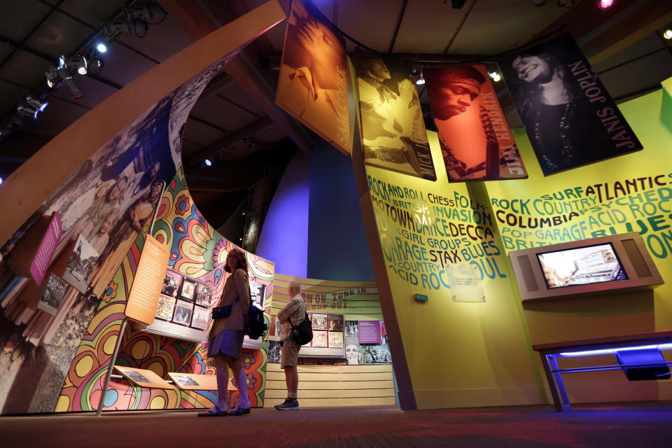 FILE - Visitors to the Museum at Bethel Woods view exhibits of the Woodstock Music and Art Fair, June 14, 2018, in Bethel, N.Y. An estimated 450,000 people attended the Woodstock festival in August 1969, and most of that crowd was composed of teenagers or young adults now in the twilight of their lives. That ticking clock is why the Museum at Bethel Woods, based at the site of the festival, is immersed in a five-year project traveling around the United States recording the oral histories of people were there, preserving the Woodstock memories before they fade away. (AP Photo/Richard Drew, File)