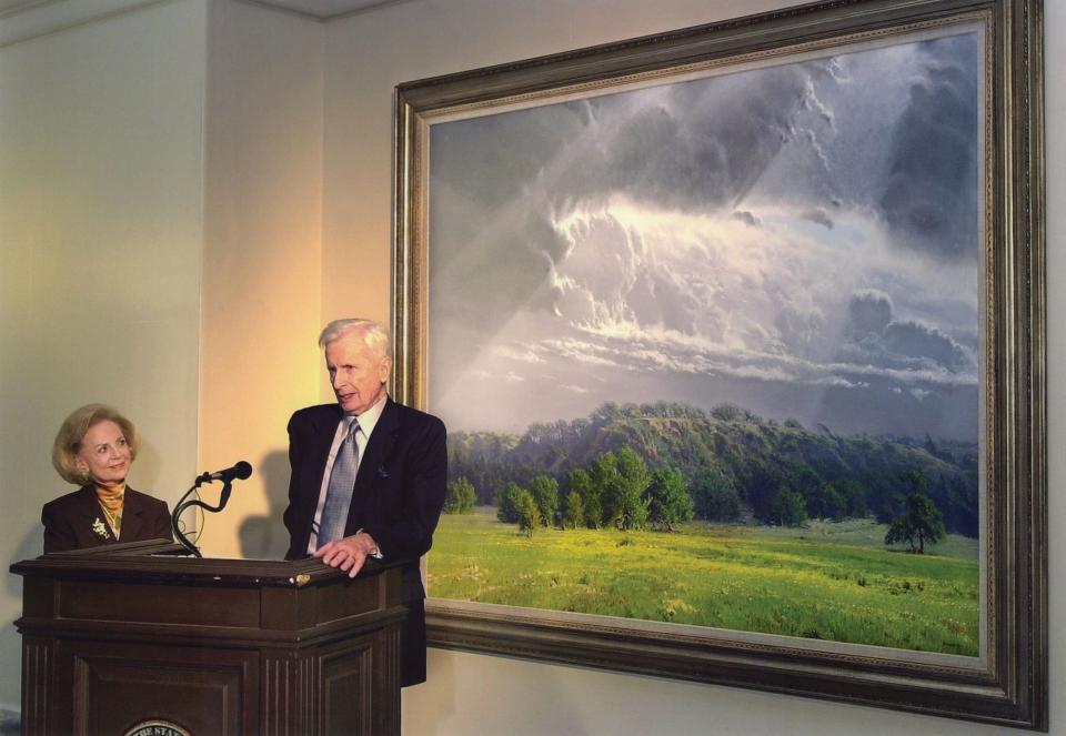 Longtime Oklahoma Arts Council Executive Director Betty Price listens to artist Wilson Hurley as he speaks about his "Visions of the Land: The Centennial Suite" landscape paintings at the state Capitol.