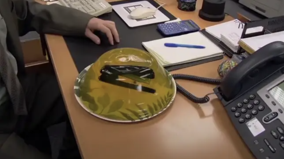 A stapler encased in clear gelatin sits on a desk, a prank scene from the TV show 'The Office'