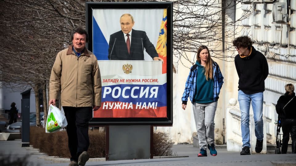 People walk in front of a poster showing Russian President Vladimir Putin and reading "The West doesn't need Russia. We need Russia!" in Simferopol, Crimea, on March 5, 2024. - AFP/Getty Images