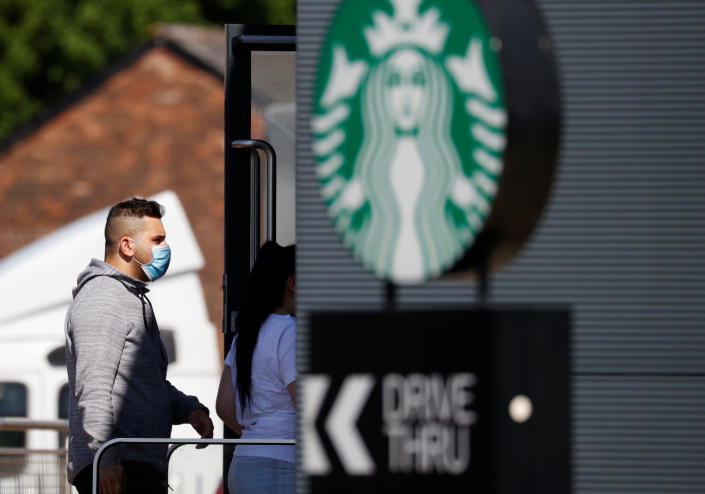 A man wearing a protective face mask is seen outside a Starbucks Coffee shop in Manchester, following the outbreak of the coronavirus disease (COVID-19), Manchester, Britain, May 14, 2020. REUTERS/Phil Noble