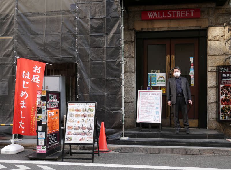 Kenichi Inoue, the owner of a restaurant named "Wall Street" stands at the entrance of the diner at Kayabacho district in Tokyo