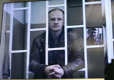 Photographer Denis Sinyakov, one of the 30 people detained after a Greenpeace protest at the Prirazlomnaya platform who is currently held at a pretrial detention centre, is seen on a screen installed inside a court building during a court session in Murmansk, October 8, 2013. REUTERS/Stringer