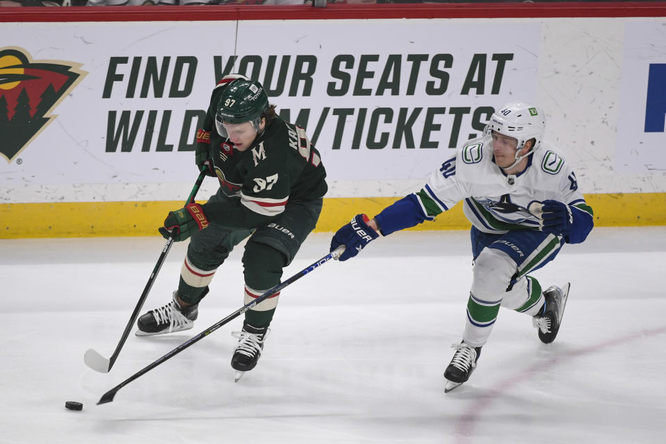 Vancouver Canucks center Elias Pettersson, right, tries to steal the puck from Minnesota Wild left wing Kirill Kaprizov during the first period of an NHL hockey game Thursday, April 21, 2022, in St. Paul, Minn. (AP Photo/Craig Lassig)