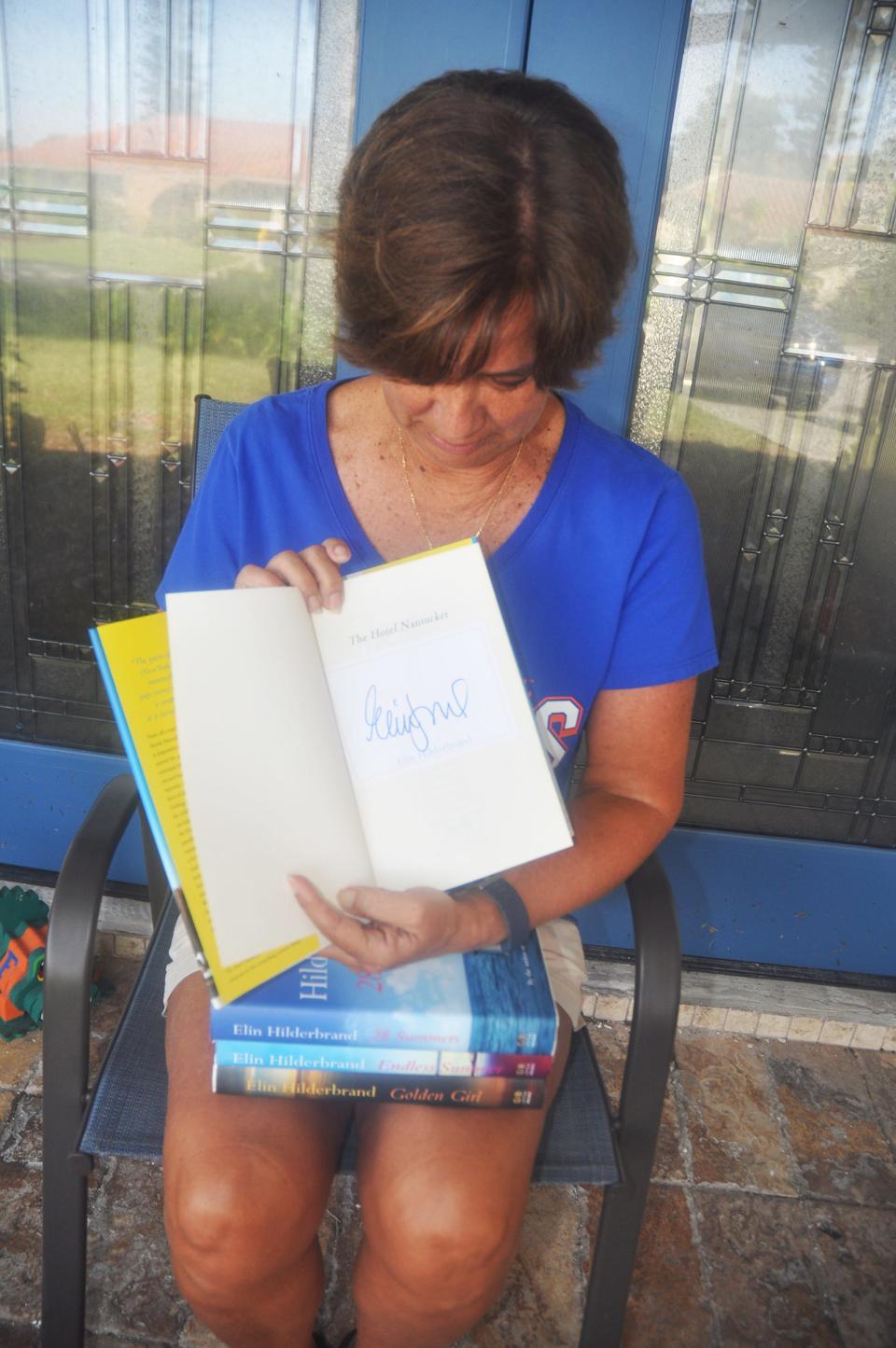 Jayne Klinker sits on the stoop of her Bonita Springs home holding the four Elin Hilderbrand books that were donated to her by the publisher. Her favorite book was autographed by the author. 