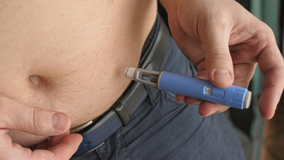 A close up of a person's belly shows them injecting themselves with semaglutide