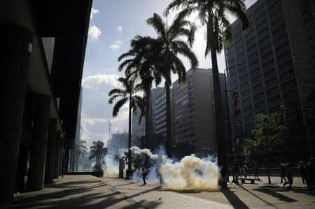People walk amidst tear gas during clashes between opposition supporters and security forces at a rally against Venezuela's President Nicolas Maduro in Caracas, Venezuela May 20, 2017. REUTERS/Carlos Barria