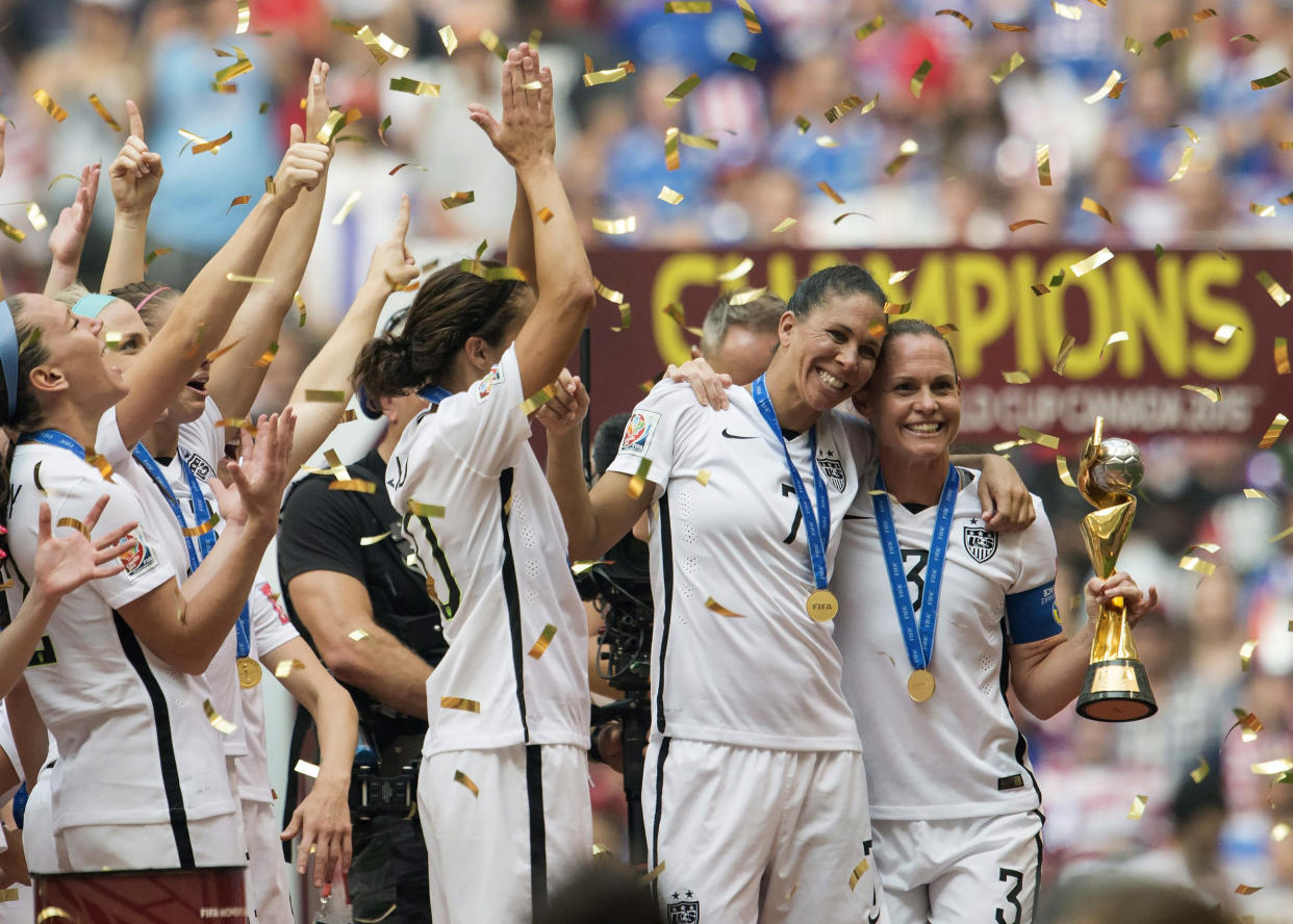 USA teammates Shannon Boxx, second from right, and Christie Rampone, far right, pose with the trophy as the USA team celebrates following their win over Japan at the FIFA Women&#39;s World Cup soccer championship in Vancouver, British Columbia, Canada, Sunday, July 5, 2015. (Jonathan Hayward/The Canadian Press via AP) 