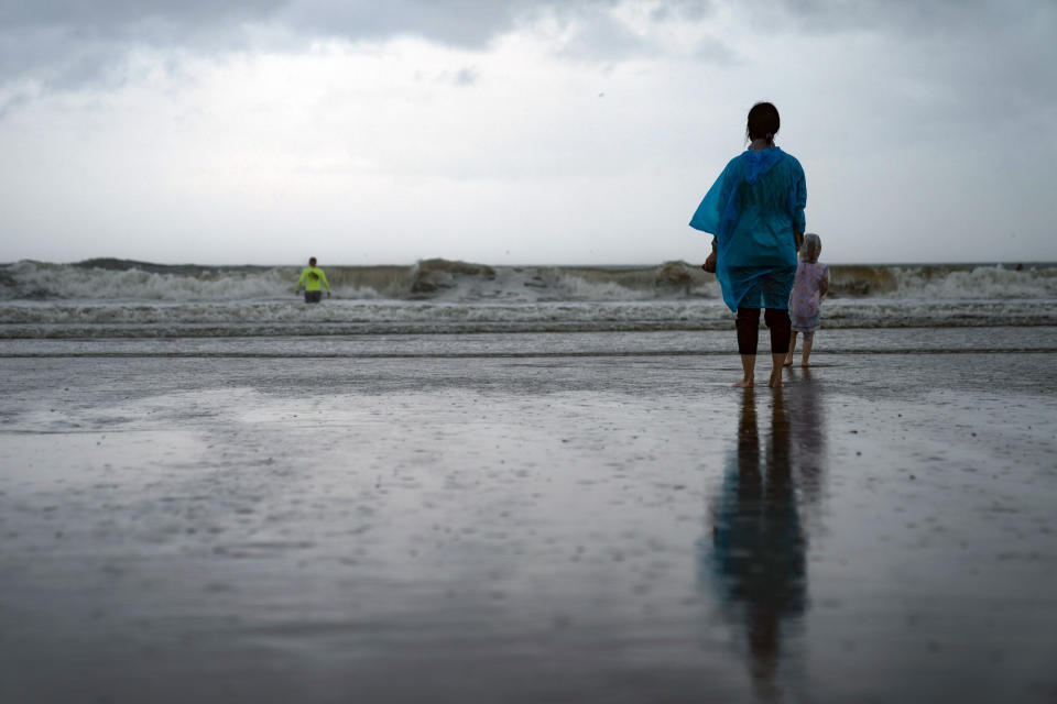 FILE - Kamila Struk, right, watches her father, Nickolas, wade into waves as Tropical Storm Henri brings strong surf and high winds to the Rockaways area of the Queens, New Yor, on Sunday Aug. 22, 2021. As weather becomes more extreme and unpredictable caused by climate change, transit officials say that more needs to be done to prepare the East Coast's vital transit systems. (AP Photo/John Minchillo, File)