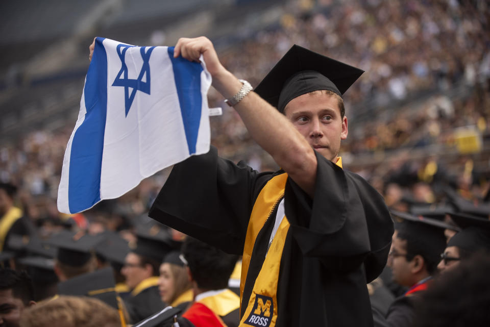 Graduates sporting Israeli flags and pins shout at Pro-Palestinian protesters as they demonstrate during the University of Michigan's Spring 2024 Commencement Ceremony at Michigan Stadium in Ann Arbor, Mich., on Saturday, May 4, 2024. (Katy Kildee/Detroit News via AP)