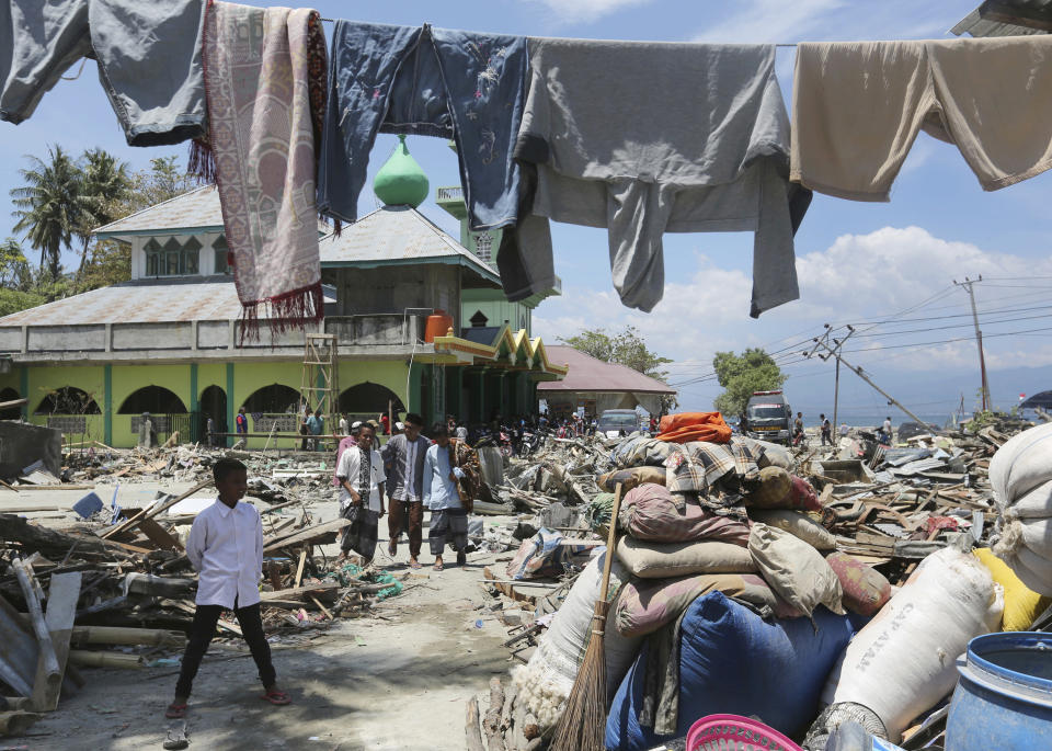 In this Friday, Oct. 5, 2018, file photo, people leave a mosque after Friday prayer surrounded by the destruction from the massive earthquake and tsunami in Loly, Central Sulawesi, Indonesia. (AP Photo/Tatan Syuflana, File)