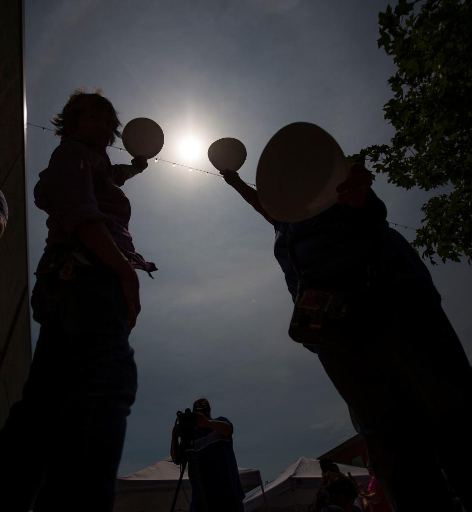 If you have a paper plate, you can poke a hole in it and let the sun shine through it to project the sun's image onto the ground during the solar eclipse, as these people apparently are doing during the eclipse on Aug. 21, 2017, at the St. Joseph County Public Library in South Bend. Don't look through the hole.