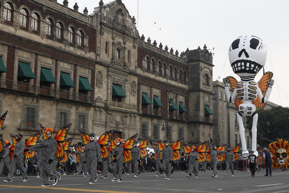 Performers in monarch butterfly costumes wave to the crowd as they walk in a Day of the Dead parade in Mexico City, Sunday, Oct. 27, 2019. The parade on Sunday marks the fourth consecutive year that the city has borrowed props from the opening scene of the James Bond film, "Spectre," in which Daniel Craig's title character dons a skull mask as he makes his way through a crowd of revelers. (AP Photo/Ginnette Riquelme)