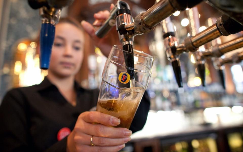 A bartender pours a pint of Fosters - Simon Dawson  /Bloomberg News  