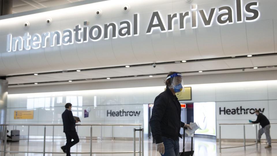 Ein Fluggast mit Mundschutz und Visier geht durch den Flughafen Heathrow.