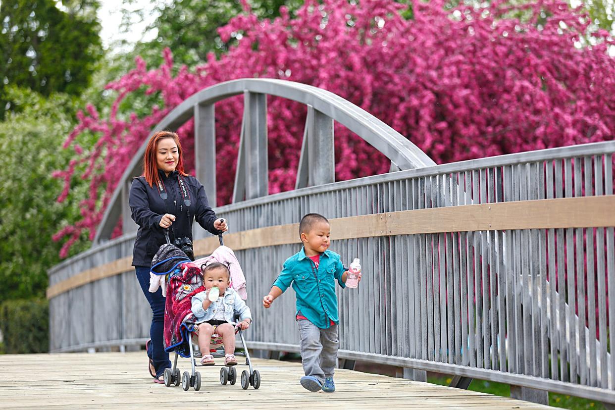 Lilly Lee, Evelyn and Aiden Xiong of Sheboygan walk across the walking bridge in Lakeside Park.