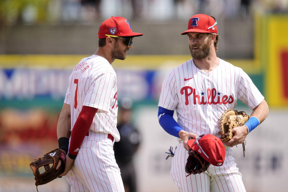 Philadelphia Phillies shortstop Trea Turner, left, talks with teammate first baseman Bryce Harper in the fifth inning of a spring training baseball game against the New York Yankees Monday, March 11, 2024, in Clearwater, Fla. (AP Photo/Charlie Neibergall)