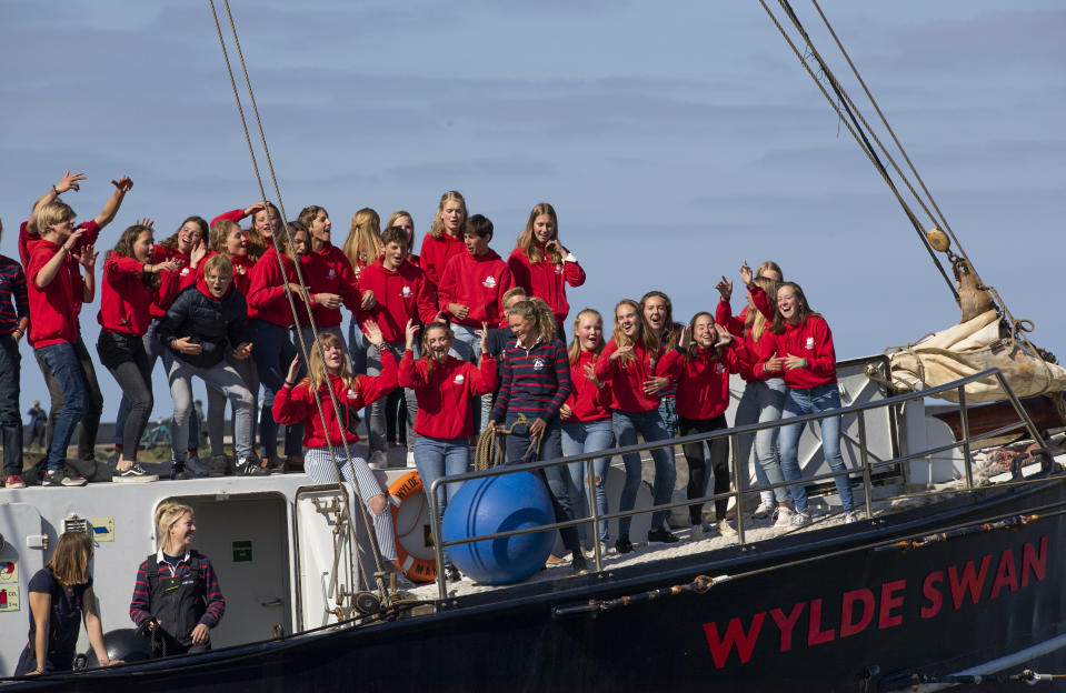 Teens cheer as their schooner carrying 25 Dutch teens who sailed home from the Caribbean across the Atlantic when coronavirus lockdowns prevented them flying arrived at the port of Harlingen, northern Netherlands, Sunday, April 26, 2020. (AP Photo/Peter Dejong)