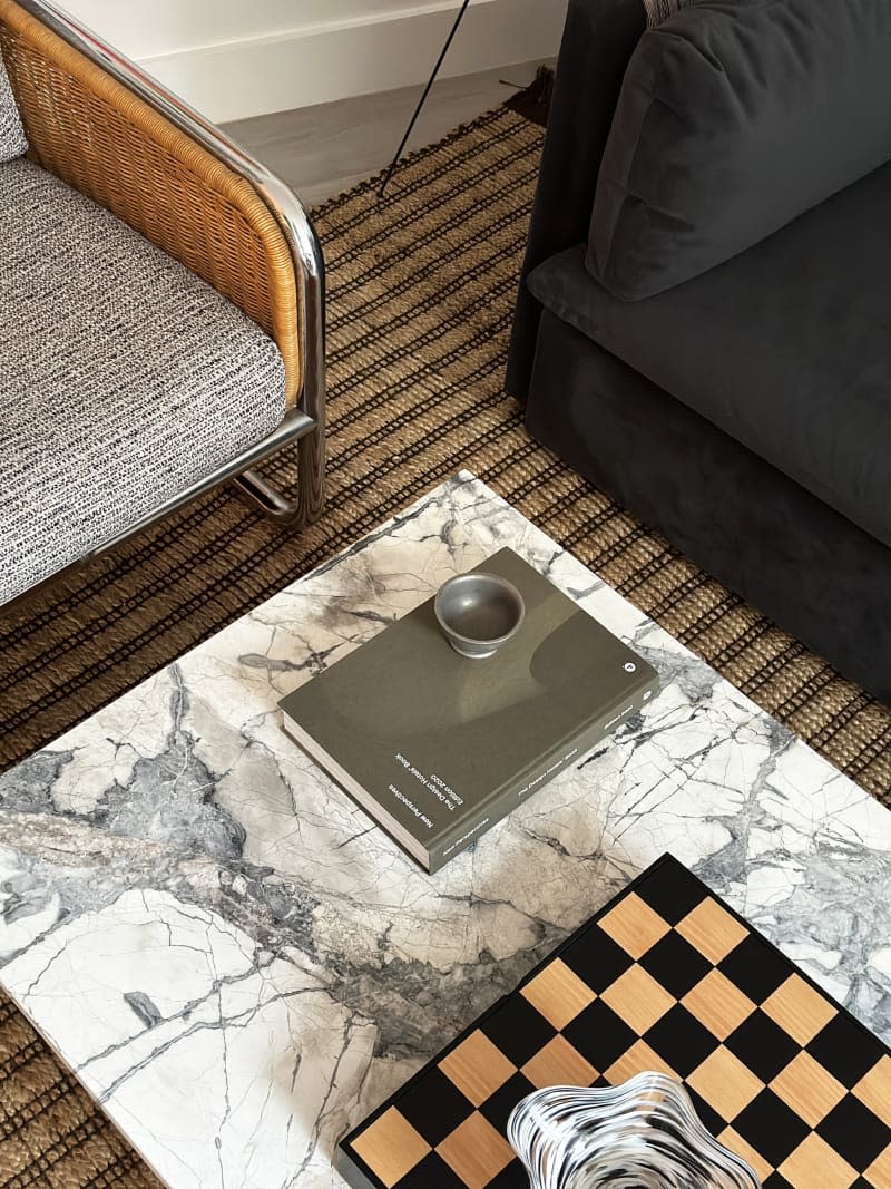 Marble-topped coffee table with fabric table and black couch.