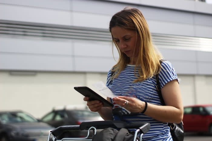 Woman in grocery store parking lot examining receipt.