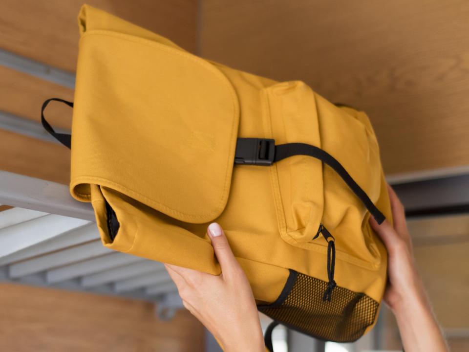 
close-up-woman-putting-backpack-train-rack