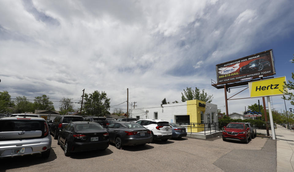 Storm clouds build over rental vehicles parked outside a closed Hertz car rental office Saturday, May 23, 2020, in south Denver. (AP Photo/David Zalubowski)