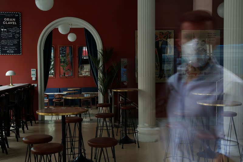 A man wearing a protective mask is reflected on the window of a closed vermouth bar, amid the coronavirus disease (COVID-19) outbreak, in Madrid