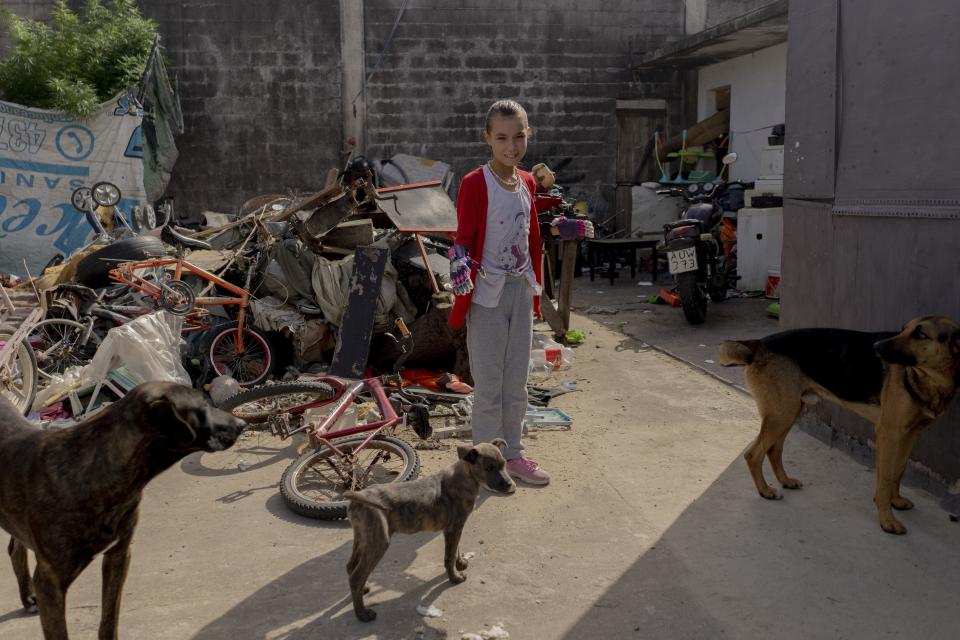 Mía Rodríguez en el patio de su casa mientras se prepara para ir a la escuela en Salinas, Uruguay, el viernes 14 de abril de 2023. Mía y su familia viven en una fábrica abandonada. (AP Foto/Matilde Campodónico)