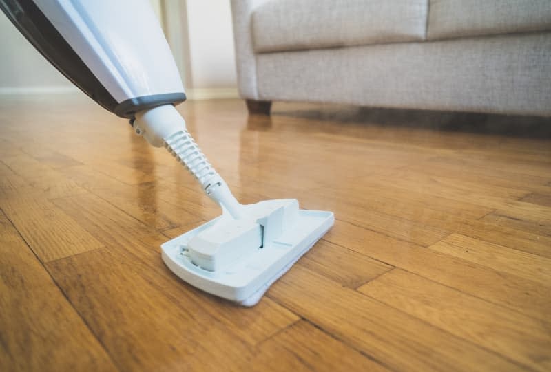 Cleaning the floor with a dry steam cleaner.