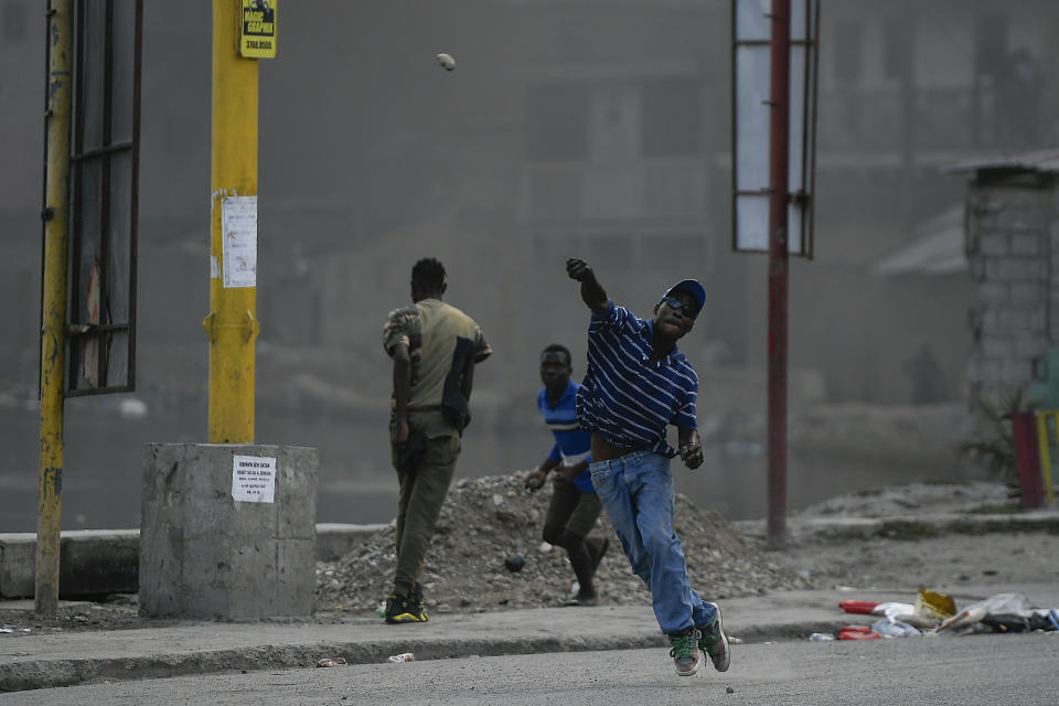 A protester demanding justice for the assassinated President Jovenel Moise hurls a stone in Cap-Haitien, Haiti, Thursday, July 22, 2021. Demonstrations after a memorial service for Moise turned violent on Thursday afternoon with protesters shooting into the air, throwing rocks and overturning heavy concrete barricades next to the seashore as businesses closed and people took cover. (AP Photo/Matias Delacroix)