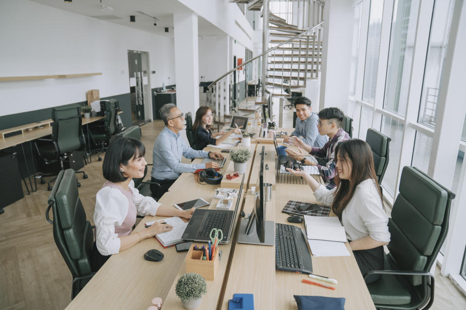 Asian white collar worker busy working and communicate in their office workstation in open plan cheerful and happily