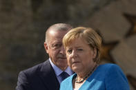 German Chancellor Angela Merkel, right, and Turkish President Recep Tayyip Erdogan arrive for their meeting at Huber Villa presidential palace, in Istanbul, Turkey, Saturday, Oct. 16, 2021. (AP Photo/Francisco Seco)
